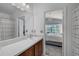 Bathroom with single sink vanity and mirror, open to bedroom with chandelier and large window at 274 Giovani Blvd, Clermont, FL 34715