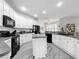Well-lit kitchen with white cabinetry, gray countertops, black appliances, and an island with a sink at 2894 Southern Pines Loop, Clermont, FL 34711