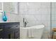 Modern bathroom featuring a freestanding tub, a cabinet with brushed gold pulls, and a window at 30236 Pga Dr, Sorrento, FL 32776