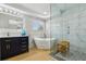 Luxurious bathroom boasting a freestanding tub, a glass-enclosed shower, and a modern vanity with gold hardware at 30236 Pga Dr, Sorrento, FL 32776