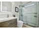 Modern bathroom featuring marble tiled shower, wood vanity, and lighted mirror for a spa-like experience at 30236 Pga Dr, Sorrento, FL 32776
