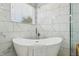 Stylish bathroom showcasing a freestanding tub, white marble-look tile, and a window for natural light and fresh air at 30236 Pga Dr, Sorrento, FL 32776