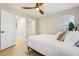 Bedroom with ceiling fan, wood-look floors, window, and a glimpse into the walk-in closet and en-suite bathroom at 30236 Pga Dr, Sorrento, FL 32776