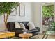 Cozy living room featuring a black sofa, accent pillows, and view of the backyard at 30236 Pga Dr, Sorrento, FL 32776
