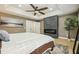Bright main bedroom featuring a stone fireplace, light hardwood floors, a ceiling fan, and a view of the ensuite at 30236 Pga Dr, Sorrento, FL 32776