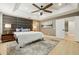 Modern main bedroom boasts a tray ceiling, wood-look floors, a padded headboard, and a view into the ensuite bathroom at 30236 Pga Dr, Sorrento, FL 32776