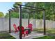 Cozy pergola with red Adirondack chairs surrounding a fire pit on a stone patio at 30236 Pga Dr, Sorrento, FL 32776