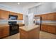 Bright kitchen with stainless steel refrigerator, oven, microwave, wooden cabinets, and center island for food preparation at 308 Anorak St, Groveland, FL 34736