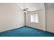 This bedroom has a window, ceiling fan, and neutral walls with bright, blue carpeting at 40325 Emeralda Island Rd, Leesburg, FL 34788
