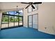 Enclosed sunroom with large windows, ceiling fans, and blue carpet at 40325 Emeralda Island Rd, Leesburg, FL 34788