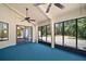 Enclosed sunroom with large windows, ceiling fans, and blue carpet at 40325 Emeralda Island Rd, Leesburg, FL 34788