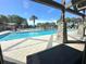View of a resort-style pool area with palm trees, lounge chairs, and stone columns at 4671 Spring Grove Ln, Leesburg, FL 34748