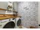 Bright laundry room featuring wood countertops, modern washer and dryer, and patterned wallpaper at 488 Avila Pl, Howey In The Hills, FL 34737