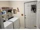 Practical laundry room equipped with a washer, dryer, storage shelves, and access to an exterior door at 4941 Tradition Dr, Lakeland, FL 33812
