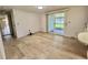 Open living room featuring light wood floors and sliding glass door to sunroom at 504 Hawthorne Blvd, Leesburg, FL 34748