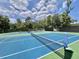 Well-maintained tennis court with clear blue skies and lush green surroundings at 504 Hawthorne Blvd, Leesburg, FL 34748