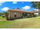 Rear exterior of home with green lawn and trimmed landscaping under a bright sky at 5209 Grove Mnr, Lady Lake, FL 32159