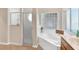 Bright bathroom featuring a soaking tub with glass block window and separate glass-enclosed shower at 5209 Grove Mnr, Lady Lake, FL 32159