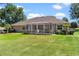 Backyard view of the home's well-maintained lawn and a screened patio at 5306 Greens Dr, Lady Lake, FL 32159