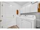 Bright laundry room features a washer, dryer, white cabinets, and a convenient side door at 5433 County Road 125, Wildwood, FL 34785