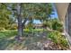 A tranquil backyard featuring lush green grass, mature trees, and a screened lanai for enjoying outdoor living at 5614 King James Ave, Leesburg, FL 34748