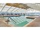 A sparkling indoor pool features large windows, a peaked glass ceiling, and tile walkways for relaxing and swimming any time of year at 5614 King James Ave, Leesburg, FL 34748