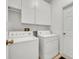 The laundry room has white appliances, storage cabinets, and tile flooring at 5614 King James Ave, Leesburg, FL 34748