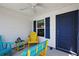Inviting screened-in porch with bright blue and yellow furnishings and a ceiling fan for added comfort at 5817 Valente Ct, The Villages, FL 32163