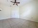 A bright bedroom with tile flooring, a ceiling fan, and a closet with white double doors at 807 Wolf Creek St, Clermont, FL 34711