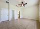Bedroom with neutral walls, tile flooring, ceiling fan, closet, and a doorway to other areas at 807 Wolf Creek St, Clermont, FL 34711
