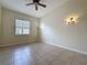 A light-filled bedroom with neutral walls, tile flooring, ceiling fan and sconce lighting at 807 Wolf Creek St, Clermont, FL 34711