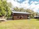 Barn with a metal roof and covered parking and additional wood structures on a grassy lot at 8091 C 476B, Bushnell, FL 33513