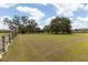 Home on a sprawling green lot with mature trees and a wooden fence perimeter at 8091 C 476B, Bushnell, FL 33513