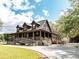 Home with wraparound porch, wood and stone siding, landscaped entrance, and concrete driveway at 8091 C 476B, Bushnell, FL 33513
