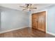 Bedroom with wood floors, ceiling fan, and large wooden closet doors at 830 Palm Harbor Ct, Leesburg, FL 34748