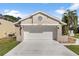 Traditional home with neutral stucco, a two-car garage, and an architectural circle detail at 830 Palm Harbor Ct, Leesburg, FL 34748