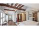 Bright bedroom showcasing exposed beams, hardwood floors, and a view leading to the attached bathroom at 908 N Tremain St, Mount Dora, FL 32757