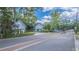 View of the home and detached garage from across a quiet street with mature trees lining the property at 908 N Tremain St, Mount Dora, FL 32757