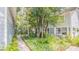 Lush yard with mature trees, a stone pathway, and well-maintained landscaping around the exterior of the home at 908 N Tremain St, Mount Dora, FL 32757