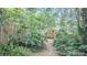 Serene backyard view featuring a pathway, lush greenery, and shade trees at 908 N Tremain St, Mount Dora, FL 32757