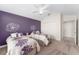 Cozy bedroom with twin beds, purple accent wall, and carpeted floors at 1016 Pickering Path, The Villages, FL 32163