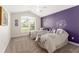 Bright bedroom with twin beds, purple accent wall, and ceiling fan at 1016 Pickering Path, The Villages, FL 32163