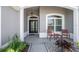 Cozy front porch with seating and a stylish front door and manicured landscaping at 1016 Pickering Path, The Villages, FL 32163