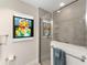 Close up of glass enclosed shower with gray tile and decorative artwork in the bathroom at 1016 Pickering Path, The Villages, FL 32163