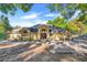 Stunning single-story home featuring a well-manicured lawn, mature trees, and an inviting entrance with large windows at 10640 Parkway Dr, Clermont, FL 34711