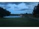 Picturesque lake view with green lawn and white fence in foreground, water and houses in background at 10640 Parkway Dr, Clermont, FL 34711