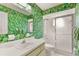 Vibrant bathroom with jungle-themed wallpaper, vanity, and a glass-enclosed shower at 10683 Se 174Th Loop, Summerfield, FL 34491