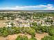 Overhead view of homes with green lawns, mature trees, with a view of the distant lake and blue skies above at 13546 Biscayne Grove Ln, Grand Island, FL 32735