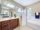 Bathroom with a double sink vanity, glass enclosed shower and a soaking tub with tile surround at 13546 Biscayne Grove Ln, Grand Island, FL 32735