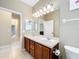 Bathroom featuring a double sink vanity, adjacent hallway, and ample lighting creating a bright and functional space at 13546 Biscayne Grove Ln, Grand Island, FL 32735